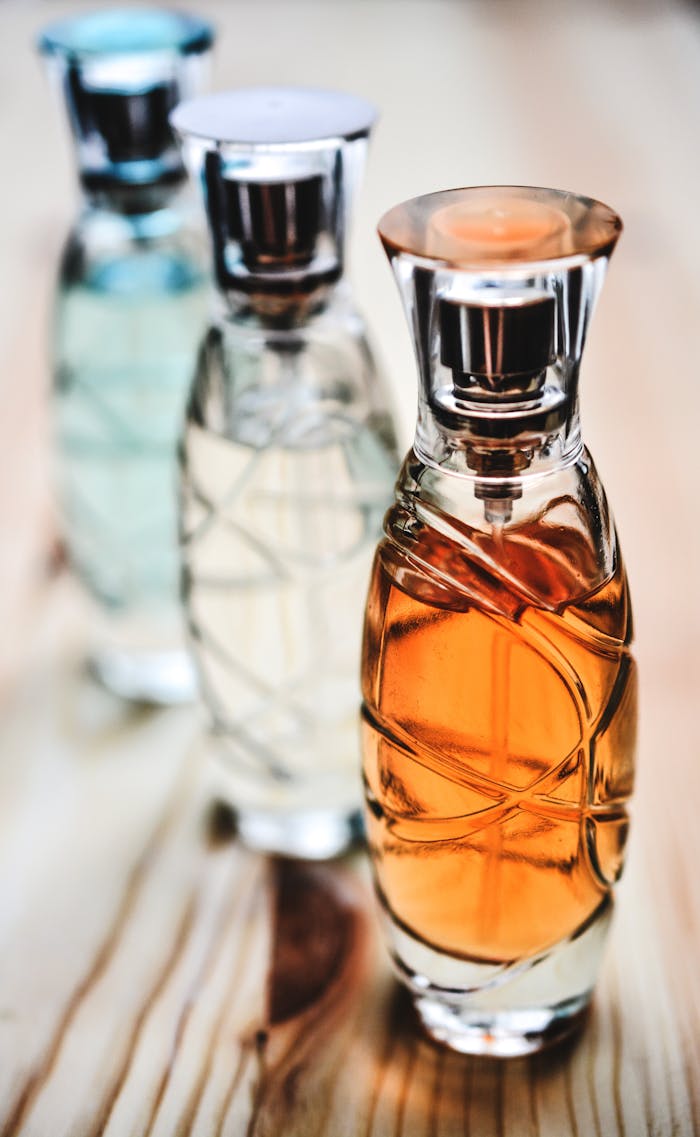 Services-03 Beautiful collection of glass perfume bottles showcasing different fragrances on a wooden surface.