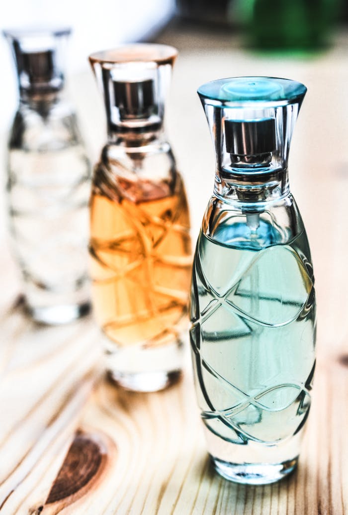 creative Artistic shot of elegant perfume bottles with colorful liquids on a wooden surface.